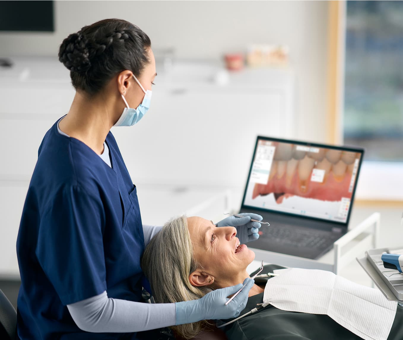 A dentist using a TRIOS scanner with a patient in a clinical setting.